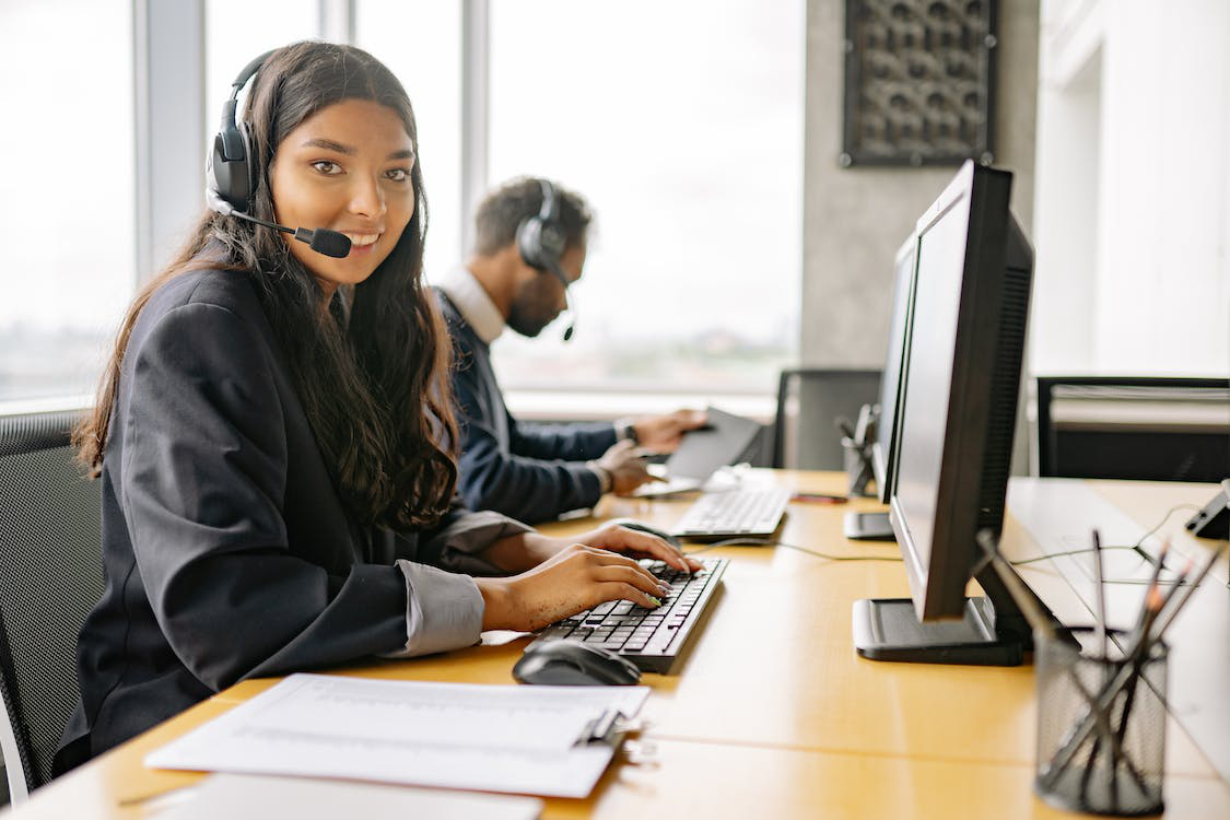 A smiling woman working in a call center while looking at the camera